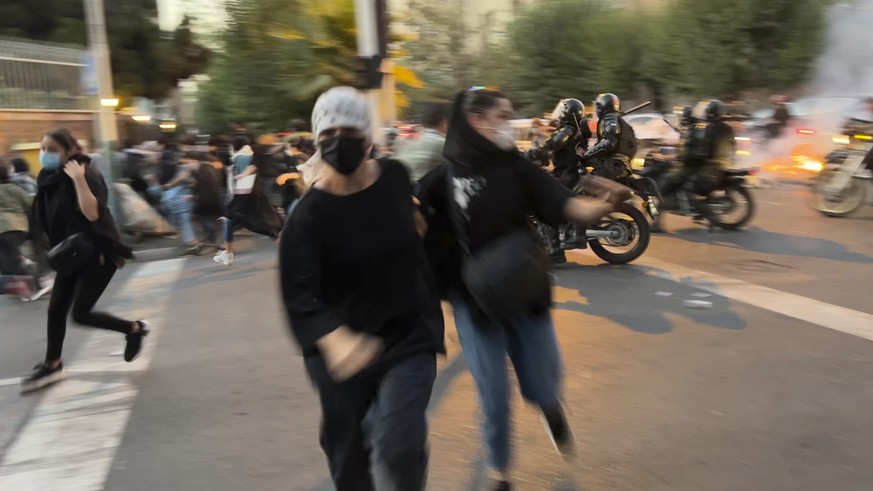In this Monday, Sept. 19, 2022, photo taken by an individual not employed by the Associated Press and obtained by the AP outside Iran, women run away from anti-riot police during a protest of the deat ...