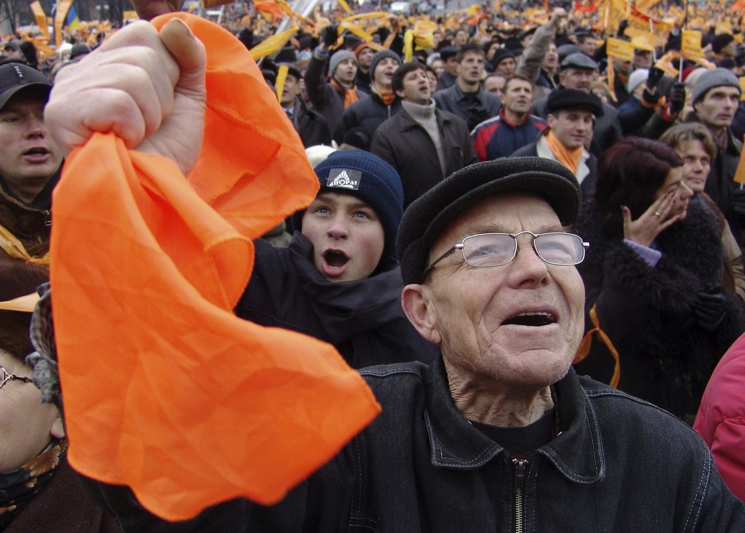 A supporter of Ukraine's then opposition leader and current Ukrainian President Viktor Yushchenko waves orange flags during a street protest in downtown Kiev, in this Nov. 22, 2004, file photo. A ...