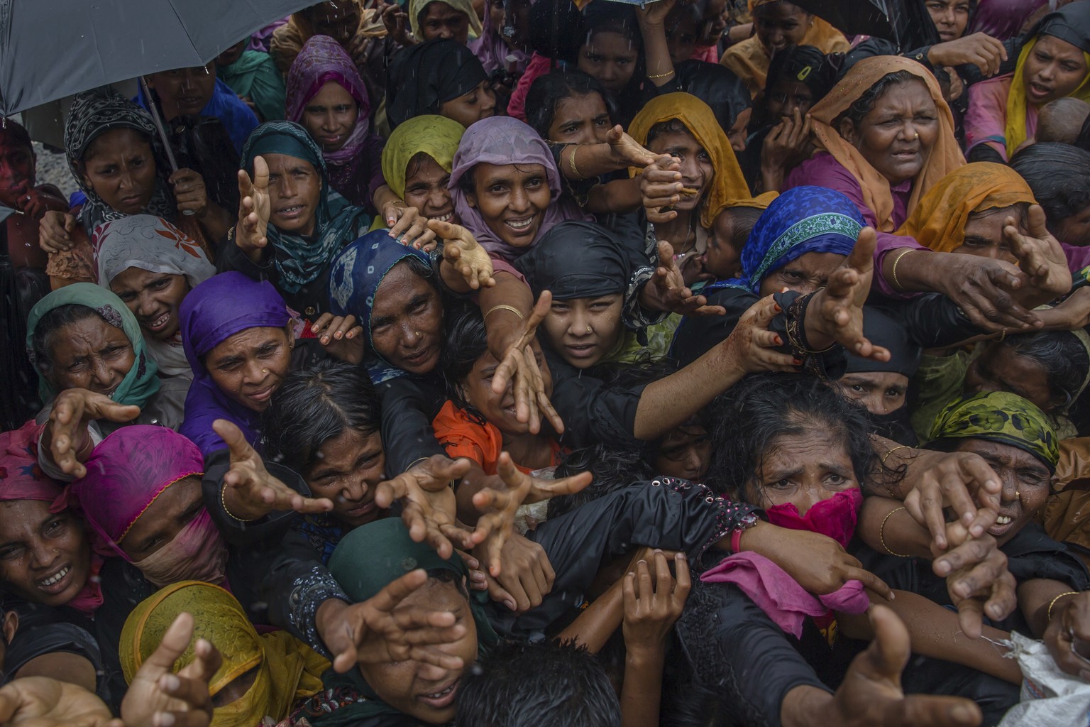 FILE - In this Sept. 17, 2017, file photo, Rohingya Muslim women, who crossed over from Myanmar into Bangladesh, stretch their arms out to collect sanitary products distributed by aid agencies near Ba ...