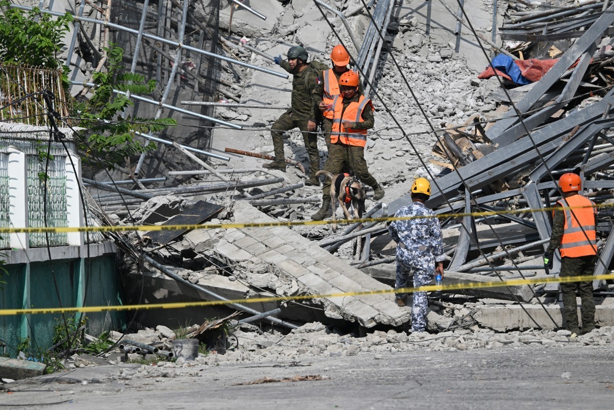 Military personnel with a working dog conduct search and rescue operations at a collapsed building in Angeles City, Pampanga province, north of Manila on May 25, 2026. The death toll rose to three on  ...