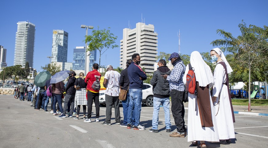 Nuns, asylum seekers and foreign workers wait in line to receive their first dose of the Pfizer-BioNTech coronavirus vaccine at a vaccination center in Tel Aviv, Israel, Tuesday, Feb. 9, 2021. Tel Avi ...