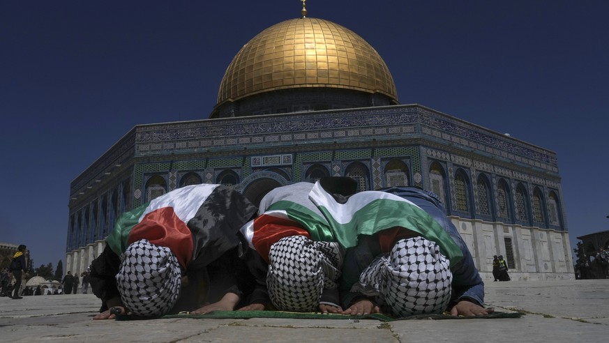 Muslim worshippers wrapped in the Palestinian flags pray during holy Islamic month of Ramadan in front of the Dome of the Rock shrine at the Al Aqsa Mosque compound in Jerusalem&#039;s Old City, Frida ...