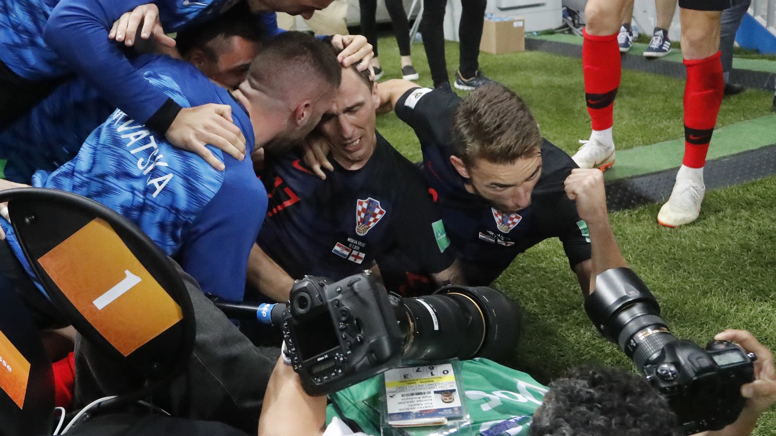 Croatia&#039;s Mario Mandzukic sits between his teammates after falling over a photographer when celebrating after scoring his side&#039;s second goal during the semifinal match between Croatia and En ...