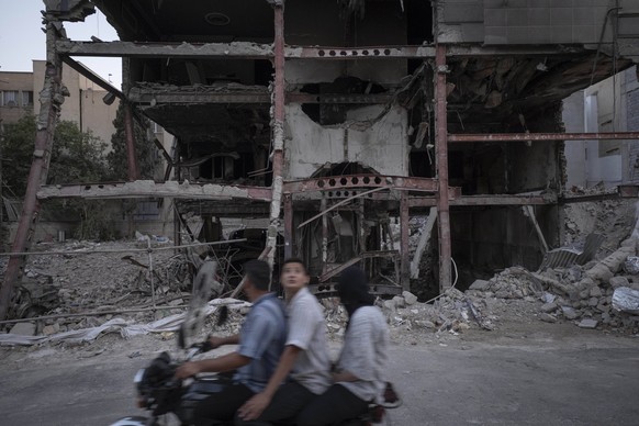 Iran-Israel War And People An Iranian family rides a motorcycle past a building that is targeted and destroyed in Israeli attacks in Tehran, Iran, on August 15, 2025. Tehran Tehran Iran PUBLICATIONxNO ...