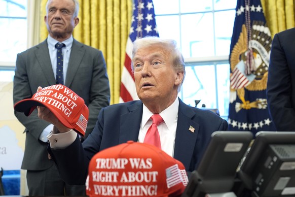 epa11924657 US President Donald Trump (R) holds a hat reading &#039;Trump was right about everything&#039; alongside Health and Human Services Secretary Robert F. Kennedy Jr. after signing executive o ...