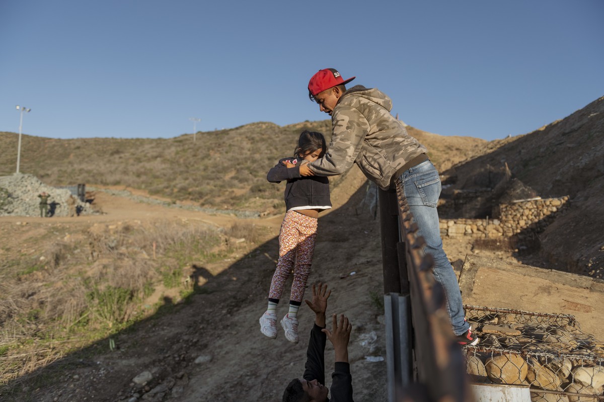 A migrant from Honduras pass a child to her father after he jumped the border fence to get into the U.S. side to San Diego, Calif., from Tijuana, Mexico, Thursday, Jan. 3, 2019. Discouraged by the lon ...