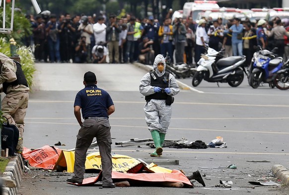 epa05101032 Members of the Indonesian Dockter Police stand near dead victims after a bomb blast in front of a shopping mall in Jakarta, Indonesia, 14 January 2016. Explosions near a shopping centre in the Indonesian capital Jakarta killed at least three people on Thursday, television reports and witnesses said. Police exchanged fire with suspected attackers after the blasts at a traffic police post in front of the Sarinah shopping centre and a nearby Starbucks coffee shop, media reported.  EPA/BAGUS INDAHONO ATTENTION EDITORS: GRAPHIC CONTENT