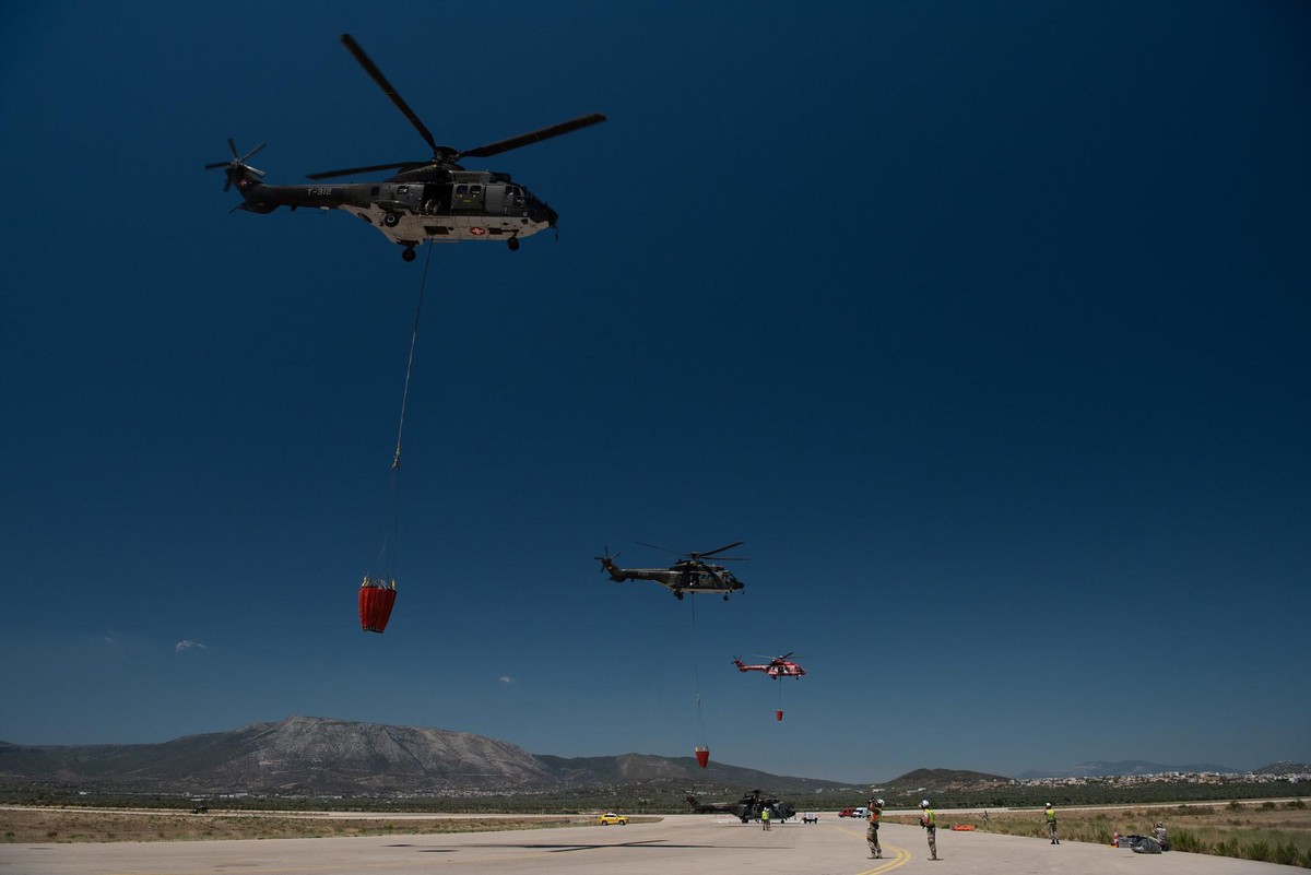 Schweizer Super-Puma-Helikopter fliegen mit Löschbehälter Richtung Einsatzgebiet bei der griechischen Insel Euböa.