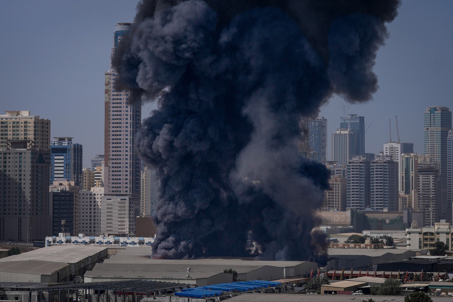 A black plume of smoke rises from a warehouse at the industrial area of Sharjah City in the United Arab Emirates following reports of Iranian strikes in Dubai, United Arab Emirates, Sunday, March 1, 2 ...