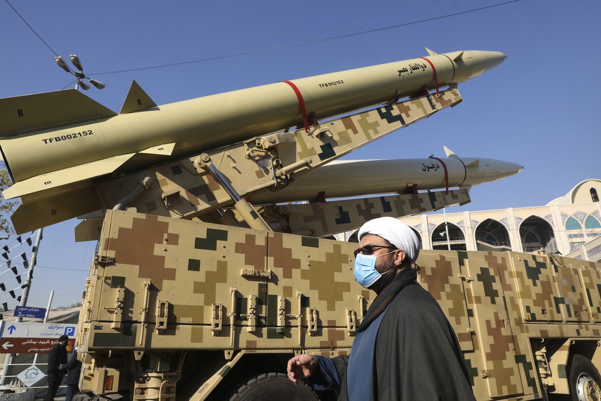 ADDS NAME OF MISSILES - A cleric walks past Zolfaghar, top, and Dezful missiles displayed in a missile capabilities exhibition by the paramilitary Revolutionary Guard a day prior to second anniversary ...