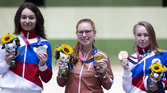 Gold medal winner Nina Christen of Switzerland, center, silver medal winner Yulia Zykova of ROC, left, and bronze medal winner Yulia Karimova of ROC, right, pose after the women&#039;s shooting 50m Ri ...