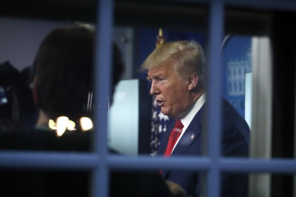 As seen through a window, President Donald Trump speaks about the coronavirus in the James Brady Press Briefing Room of the White House, Tuesday, March 31, 2020, in Washington. (AP Photo/Alex Brandon) ...