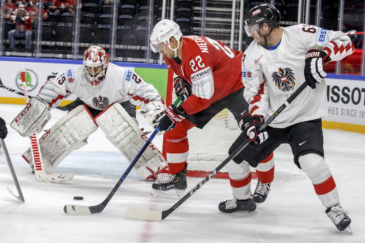Switzerland's forward Nino Niederreiter, center, vies for the puck with Austria's defender Markus Schlacher, right, past Austria's goaltender Bernhard Starkbaum, left, during the IIHF 2 ...