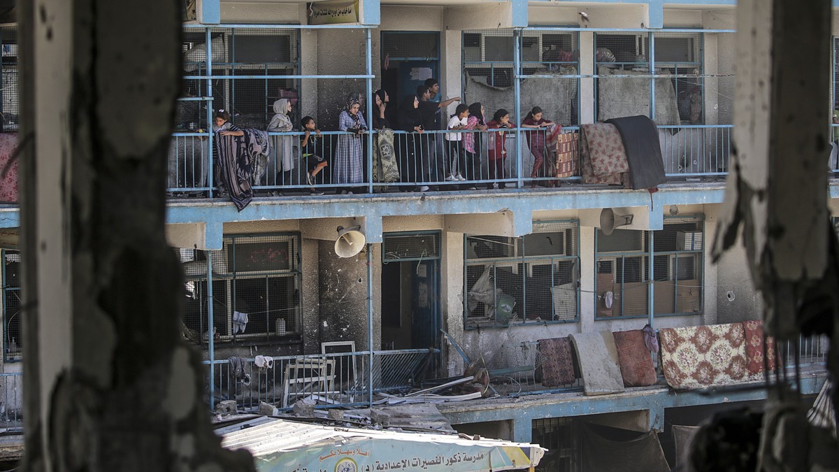 epa11392969 Internally displaced Palestinians look out from the balcony of a damaged UNRWA school building following an Israeli airstrike in Al Nusairat refugee camp in the central Gaza Strip on, 06 J ...