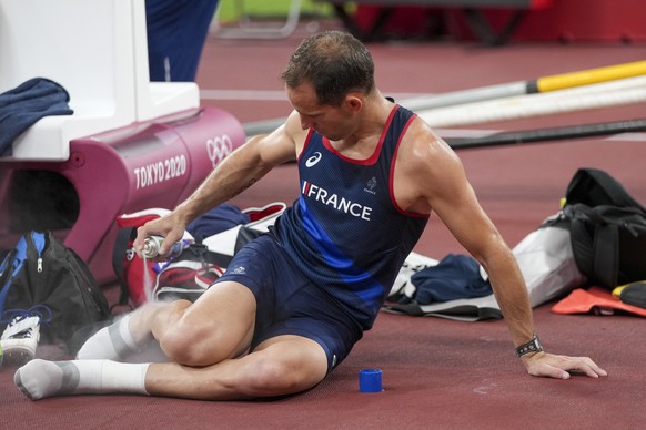 Renaud Lavillenie, of France, uses ice spray after a fall during warn ups before the men&#039;s pole vault final at the 2020 Summer Olympics, Tuesday, Aug. 3, 2021, in Tokyo. (AP Photo/Matthias Schrad ...