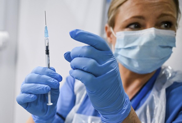 Paula McMahon prepares a shot of the Pfizer-BioNTech COVID-19 vaccine, as the mass public vaccination program gets underway, at the NHS Louisa Jordan Hospital in Glasgow, Scotland, Tuesday Dec. 8, 202 ...