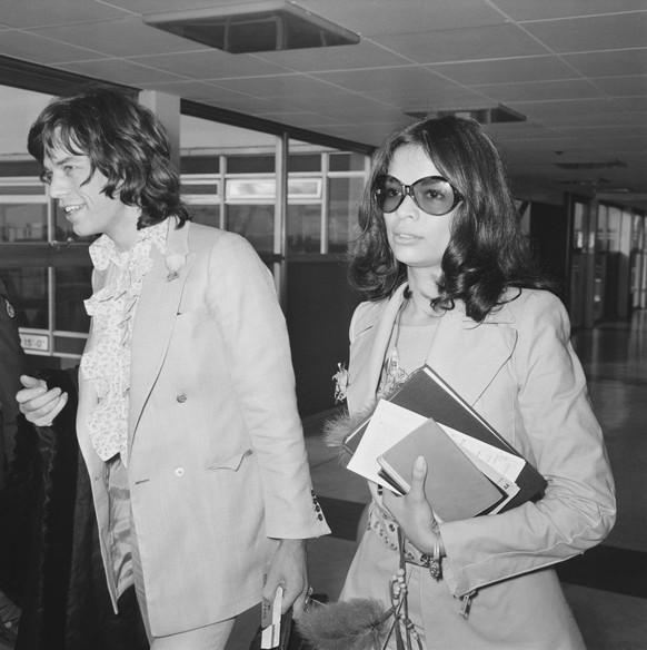Mick Jagger of the Rolling Stones and his girlfriend Bianca Perez-Mora Macias arrive at London&#039;s Heathrow Airport to catch a flight to the Bahamas for a holiday, 25th November 1970. (Photo by Eve ...