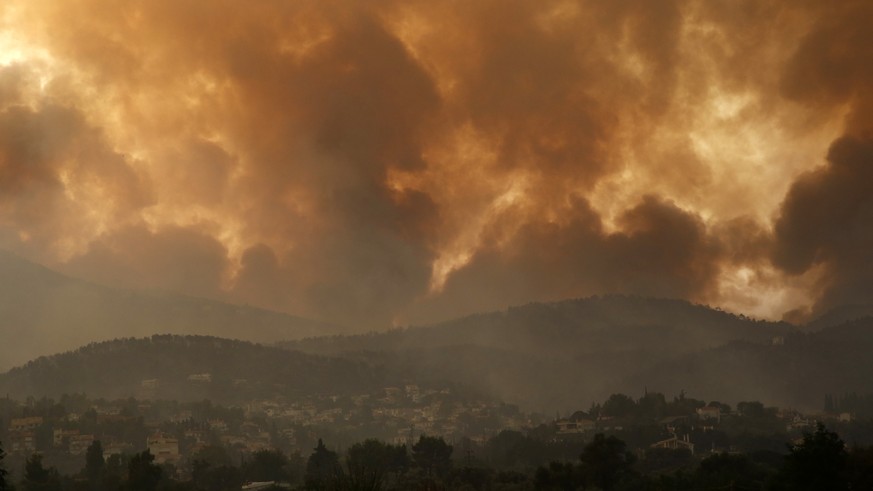 Smoke spreads over Parnitha mountain during a wildfire in Ippokratios Politia village, about 35 kilometres (21 miles), northern Athens, Greece, Friday, Aug. 6, 2021. Thousands of people fled wildfires ...