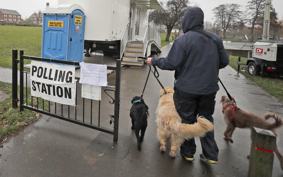 A voter with his dogs arrives at a polling station in Twickenham, London, Thursday, Dec. 12, 2019. Dogs and British people go out in the winter to vote, at various places during Britain&#039;s general ...