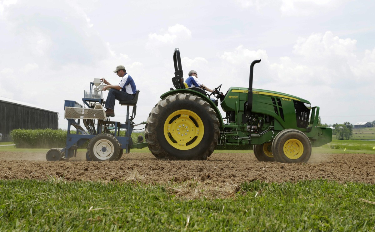 Richard Mundell, left, sits on a plot seeder pulled by a tractor driven by Mark Sizemore, as they plant hemp seeds at the UK Spindletop Research Farm off of Newtown Pike in Lexington, Ky., on Tuesday, ...