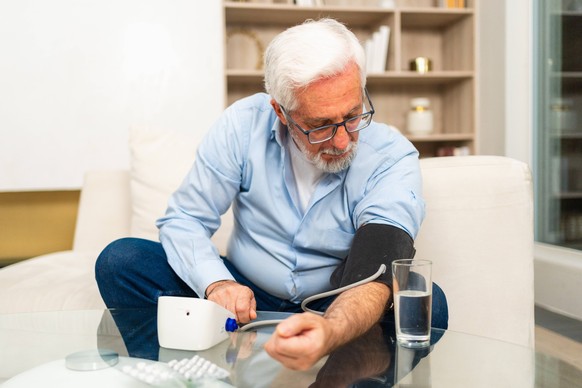 Bluthochdruckproblem im Seniorenalter. Alter Mann misst Blutdruck mit Tonometer zu Hause. Älterer Mann mit Gesundheitsproblemen bei der Selbstuntersuchung. Kopfschmerzen Behandlung von Bluthochdruck H ...