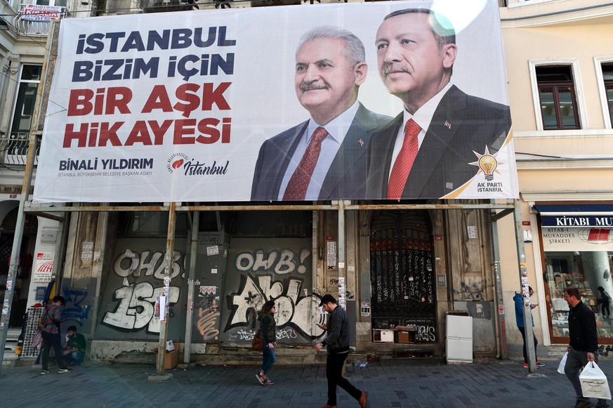 epa07466962 People walk in front of the pictures of Turkish President Recep Tayyip Erdogan (R) and Candidate of Justice and Development Party (AK Party) for Istanbul mayor Binali Yildirim (C), in Ista ...