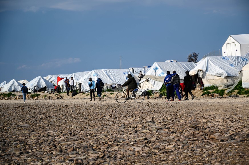 epa09105256 Migrants walk outside their tents at Karatepe refugee camp on Lesbos island, Greece, 29 March 2021. European Commissioner for Home Affairs, Ylva Johansson and Migration and Asylum Minister ...