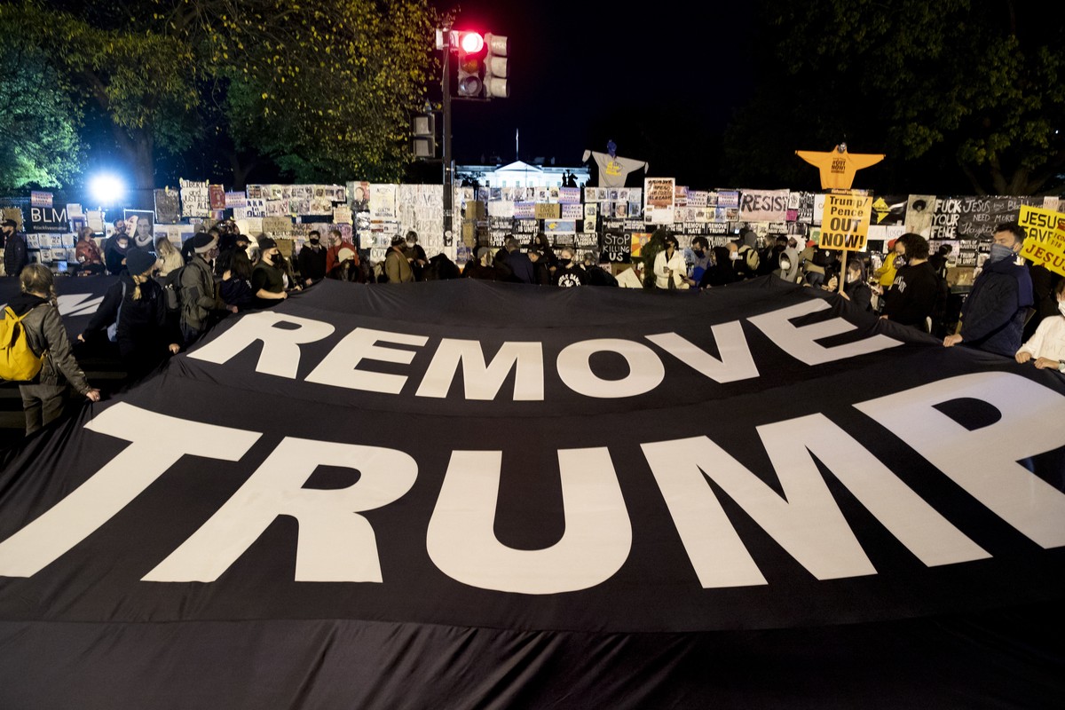 epa08797255 People hold a banner that reads 'Remove Trump', at Black Lives Matter Plaza near the White House, seen behind, in Washington, DC, USA, 03 November 2020. Americans vote on Electio ...