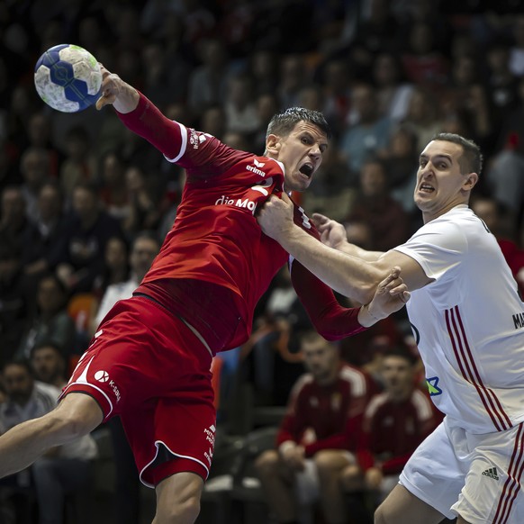 Switzerland&#039;s Andy Schmid, left, scores a goal past Hungary&#039;s Paztrick Ligetvari during the EHF Euro 2024 Men&#039;s Handball Championship qualification match between Switzerland and Hungary ...