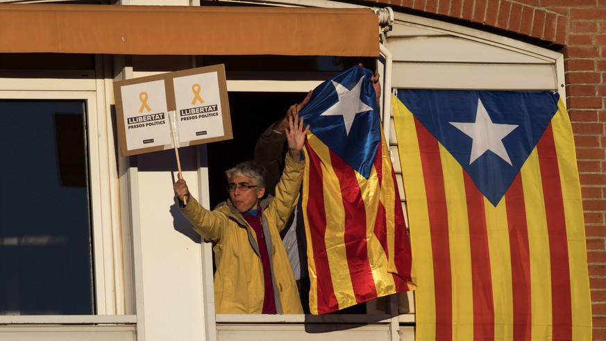 People react on a balcony as demonstrators take part at a protest calling for the release of Catalan jailed politicians, in Barcelona, Spain, on Saturday, Nov 11, 2017. Eight members of the now-defunc ...