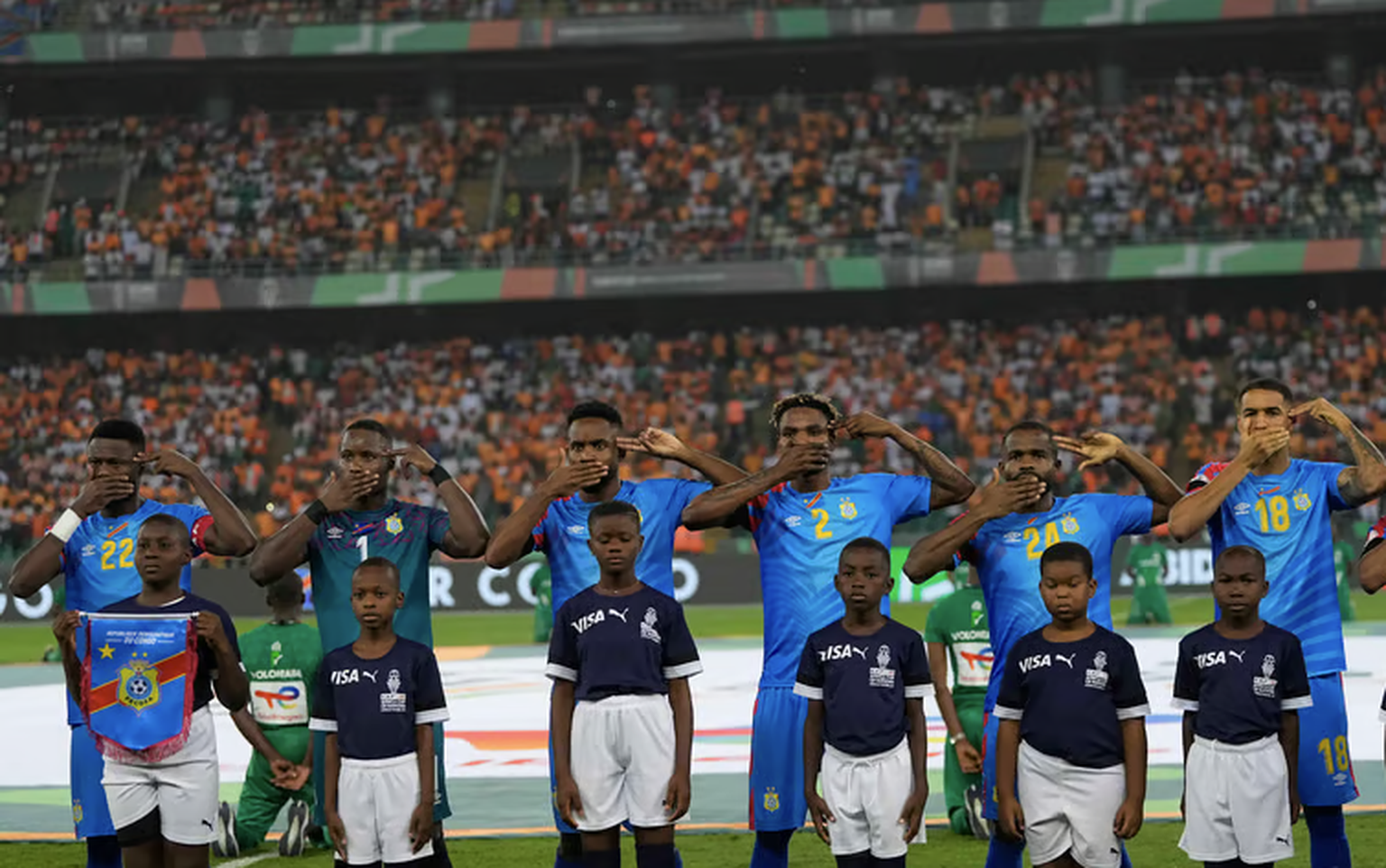 Charles Pickel (rechts) und das kongolesische Nationalteam weisen bei der Nationalhymne während des Halbfinals des Afrika-Cups auf die Bedrohung in der Heimat hin.