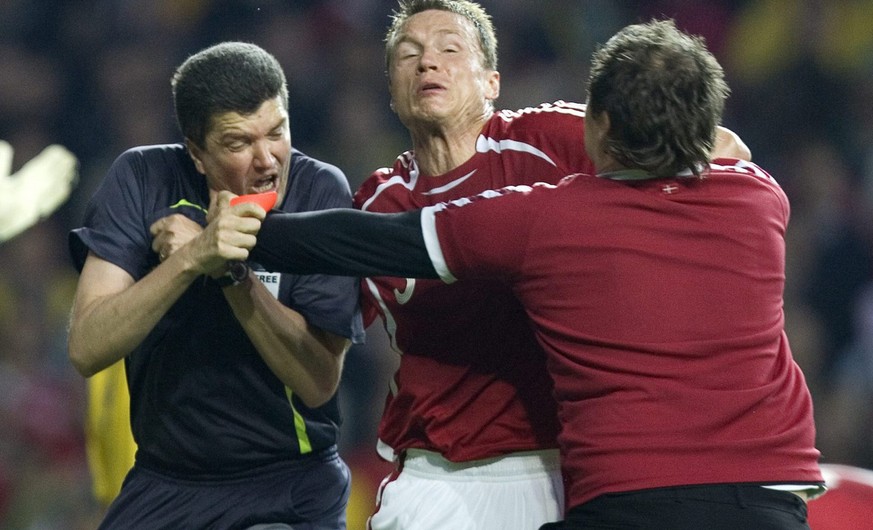 FILE - In this Saturday June 2, 2007 file photo Denmark&#039;s Michael Gravgaard, center, tries to intervene as Danish supporter Ronni Noervig attacks referee Herbert Fandel , left, for giving Sweden  ...