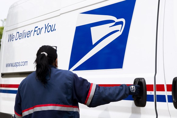 epa08389791 A mail carrier of the United States Postal Service (USPS) delivers mail to residences in Silver Spring, Maryland, USA, 28 April 2020. US President Donald J. Trump has threatened to withhol ...
