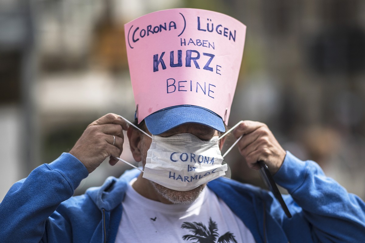 epa08382459 A participant puts on a protective face mask reading 'Corona is harmless' as he wears a sign reading '(Corona) Lies have short legs' referring to Austrian Chancellor Se ...