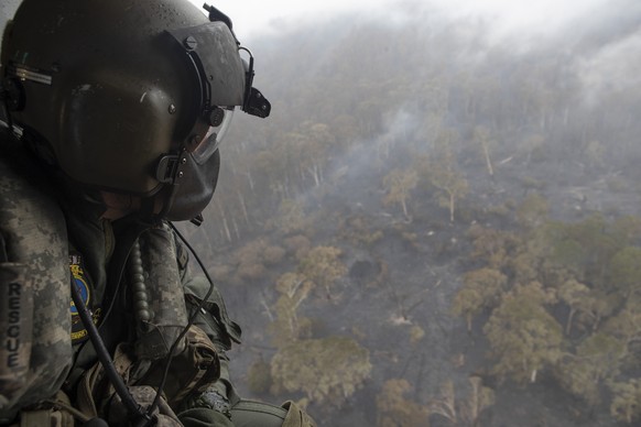 epa08109253 A handout photo made available by Australia&#039;s Department of Defence on 07 January 2020 shows leading seaman aircrew Brendan Menz looking out the door of HMAS Choules&#039; MRH-90 Mari ...