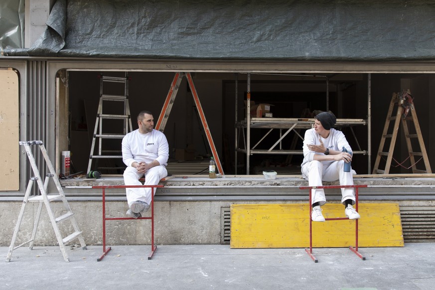 epa08309116 Two plasterers keep a safetey distance between themselves while taking a break, in Bern, Switzerland, 20 March 2020. People all over the alpine nation were invited to take part in the &#03 ...