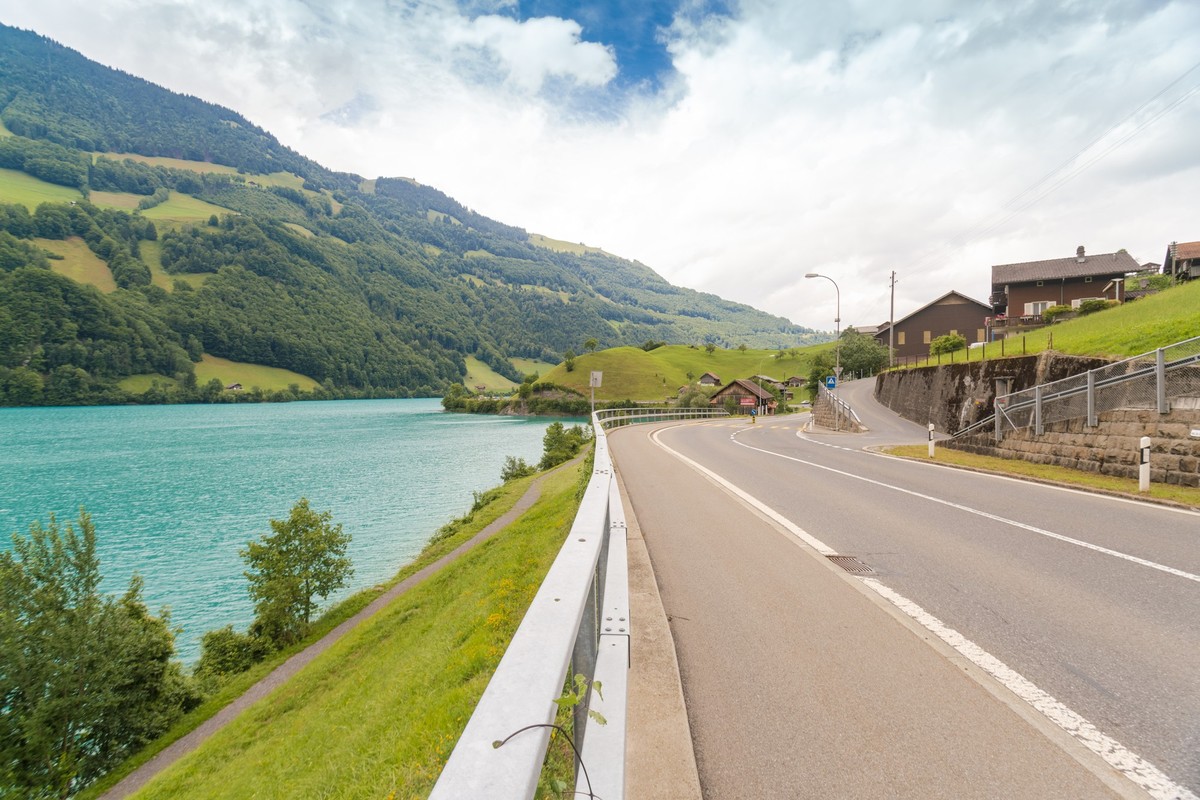Road at a village beside Lungern Lake in summer xkwx valley, mountain, blue, travel, lake, landscape, switzerland, nature, village, lungern, road, view, europe, beautiful, summer, tourism, cloud, gras ...