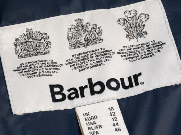 Guildford, UK - September 13, 2022: Royal Warrant of Appointment logos on the inner label of a Barbour coat jacket. Supplier of goods or services to Royal personages. By appointment to HM The Queen.