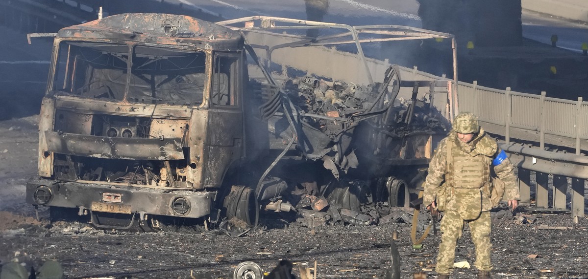 A Ukrainian soldier walks past debris of a burning military truck, on a street in Kyiv, Ukraine, Saturday, Feb. 26, 2022. Russian troops stormed toward Ukraine's capital Saturday, and street figh ...