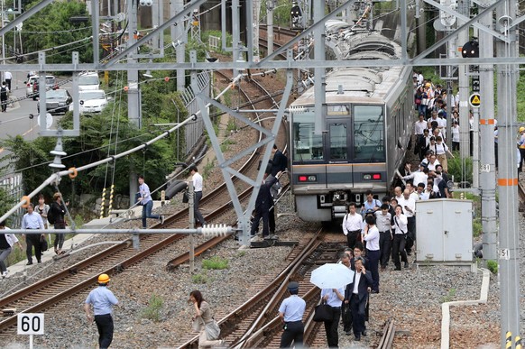 epa06817533 Passengers on board a commuter train walk on the railway due to suspended service, after a magnitude 6.1 earthquake hit western Japan, in Osaka, western Japan, 18 June 2018. EPA/JIJI PRESS ...