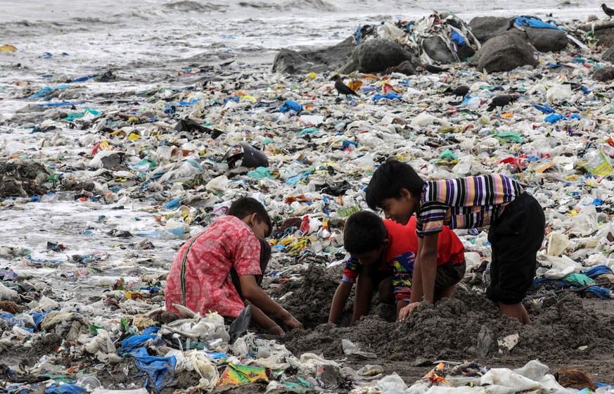 epa06831064 Indian children plays amidst left over eatables and plastic waste, near the Arabian Sea coast at Mahim beach in Mumbai, India, 22 June 2018. According to media reports, the government of t ...