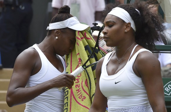 Venus Williams of the U.S.A. wipes her face as Serena Williams of the U.S.A. looks on during their match at the Wimbledon Tennis Championships in London, July 6, 2015.                  REUTERS/Toby Melville 