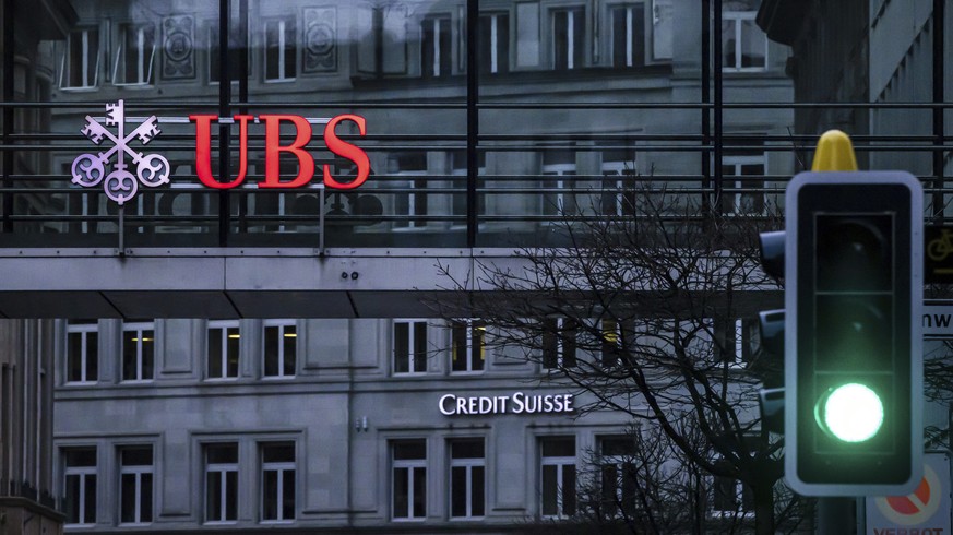 A traffic light signals green in front of the logos of the Swiss banks Credit Suisse and UBS in Zurich, Switzerland, Sunday March 19, 2023. (Michael Buholzer/Keystone via AP)