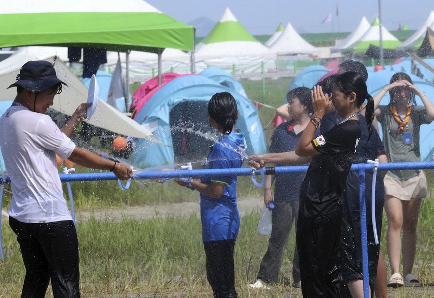 Attendees of the World Scout Jamboree cool off with water at a scout camping site in Buan, South Korea, Friday, Aug. 4, 2023. More than 100 people were treated for heat-related illnesses at the World  ...