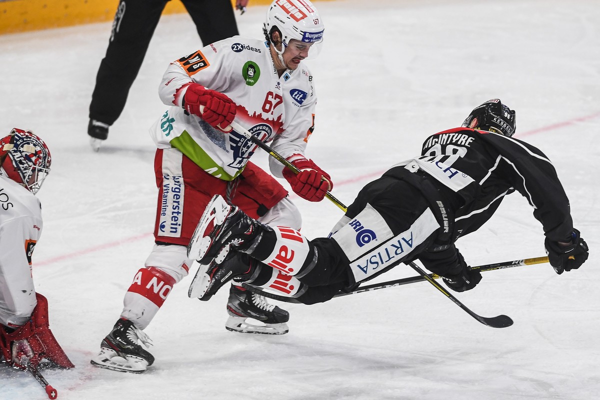 Rapperswil's player Florian Schmuckli, left, fights for the puck with Lugano?s player David McIntyre, right, during the preliminary round game of National League A (NLA) Swiss Championship 2019/2 ...