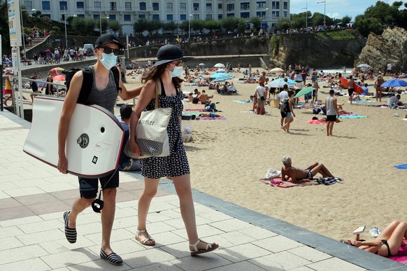 People wearing face masks at the beach in Biarritz, southwestern France, Monday July 3, 2020, as several sites around France have started requiring masks outdoors in recent days. Starting Monday, 69 t ...