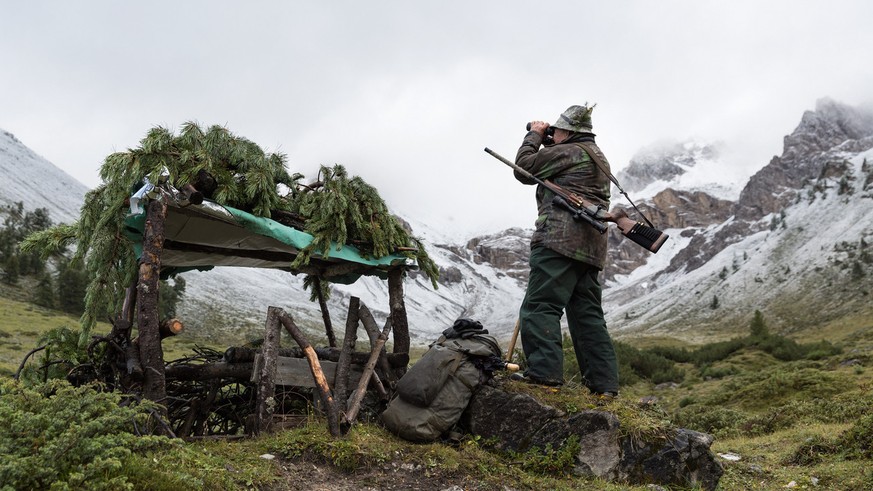 Der 71-jaehrige Jaeger Johannes Bischoff sucht zum Auftakt der Buendner Hochjagd mit seinem Feldstecher die frisch verschneiten und nebelverhangenen Flanken oberhalb Scuol im Unterengadin nach Wild ab ...