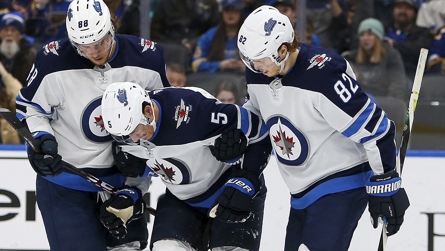 Winnipeg Jets&#039; Nathan Beaulieu (88), left, and Mason Appleton (82), right, help teammate Luca Sbisa (5), of Italy, up from the ice after Sbisa suffered an injury during the second period of an NH ...