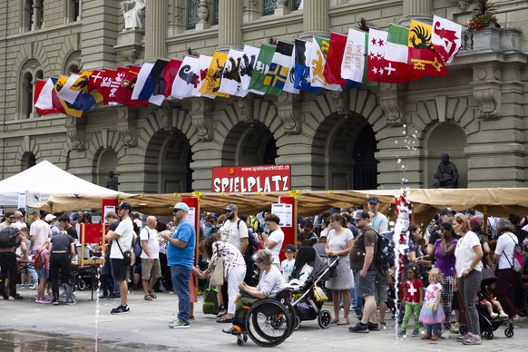 Besucher stehen beim Wasserspiel vor dem Bundeshaus, das mit den Kantonsflaggen geschmueckt wurde, waehrend der Bundesfeier, am Freitag, 1. August 2025 auf dem Bundesplatz in Bern. (KEYSTONE/Peter Kla ...