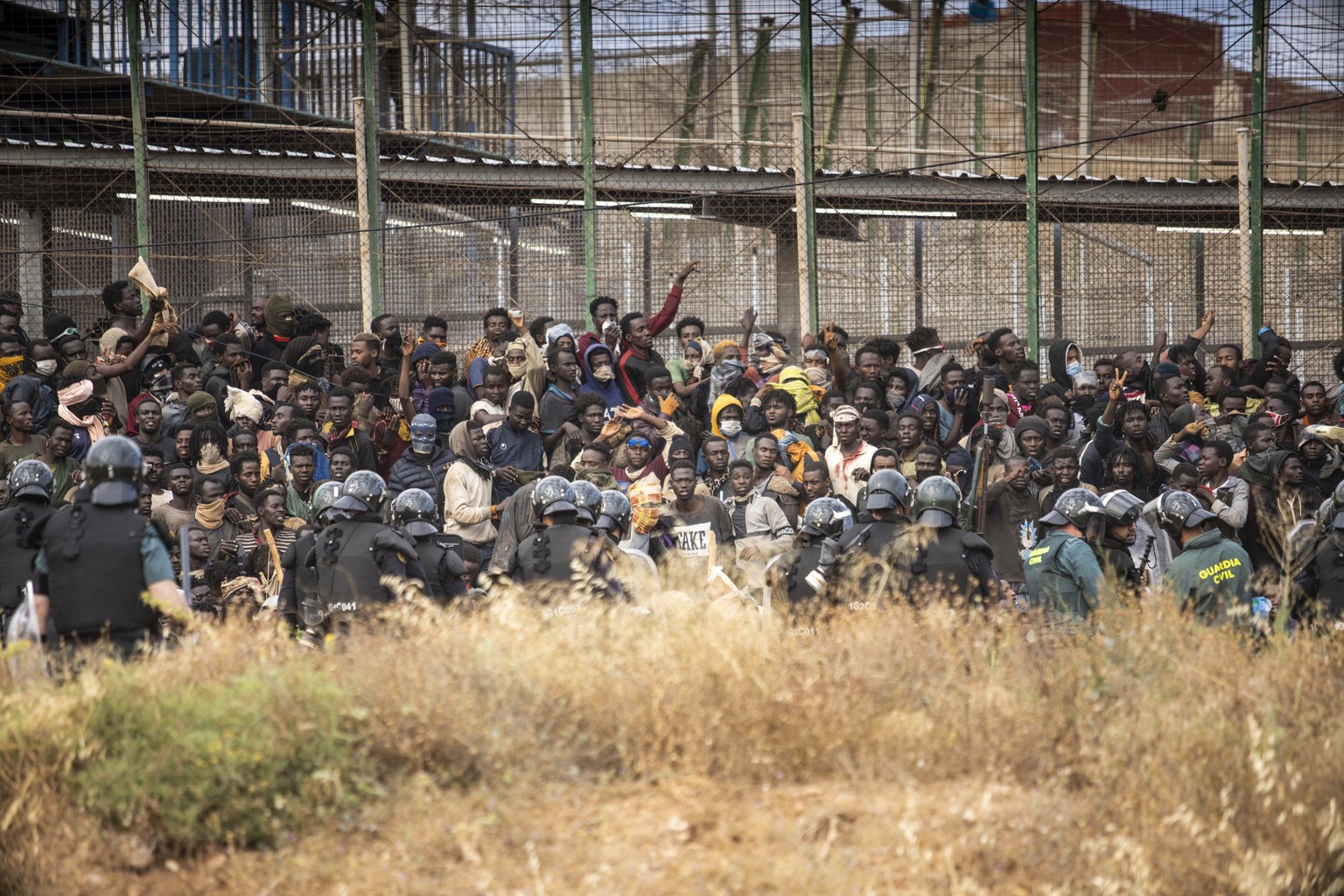 Migrants arrive on Spanish soil after crossing the fences separating the Spanish enclave of Melilla from Morocco in Melilla, Spain, Friday, June 24, 2022. Dozens of migrants stormed the border crossin ...